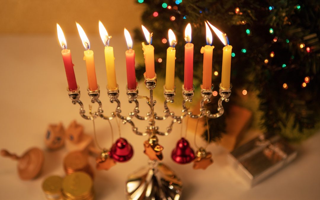 a menorah lit in front of a Christmas tree