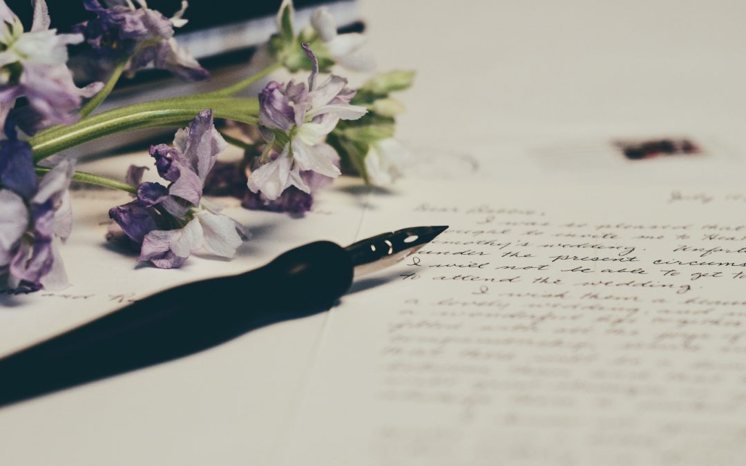 a letter, fountain pen, and purple flowers on a desk