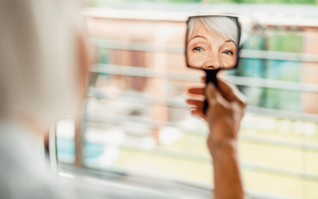 woman looking into a hand mirror to see herself