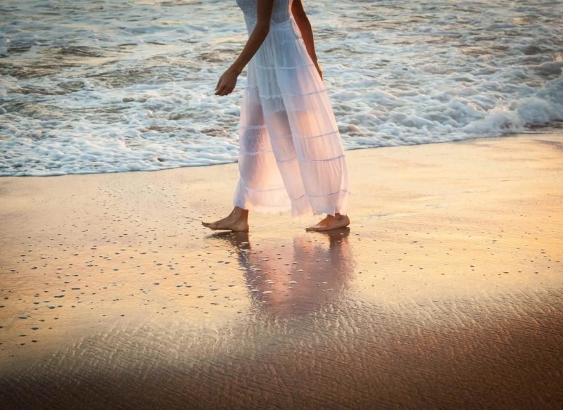 a woman in white dress walking along the water, giving a sense of self reflection