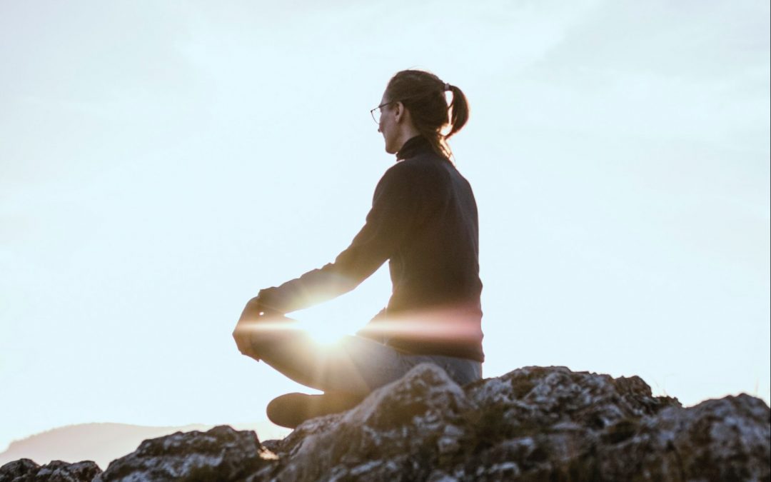 a woman meditating at sunrise to depict her overcoming societal biases.